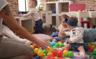 Group of toddlers playing with toys sitting on floor at kindergarten